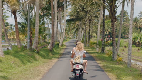 Pareja-De-Viajes-Montando-Moto-En-Una-Isla-Tropical-Mujer-Feliz-Celebrando-La-Libertad-Con-Los-Brazos-Levantados-Disfrutando-De-Un-Viaje-Por-Carretera-De-Vacaciones-Con-Su-Novio-En-La-Vista-Trasera-De-Un-Paseo-En-Motocicleta