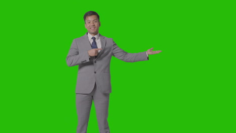 Three-Quarter-Length-Shot-Of-Businessman-In-Suit-Presenting-Or-Showing-Against-Green-Screen-2