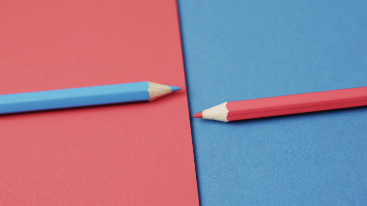 Close up of blue and red crayons arranged on red and blue background, in slow motion