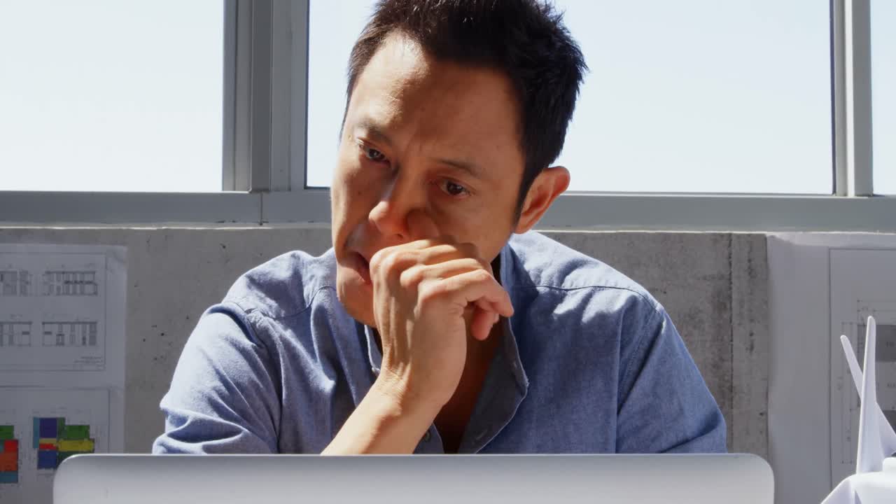 현대 사무실 4k에서 책상 위에 노트북을 사용하는 아시아 남성 건축가의 전면 전망