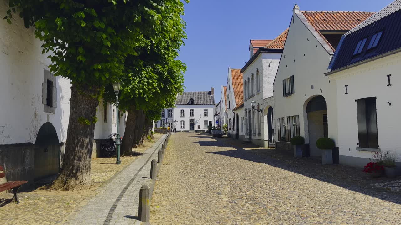Static shot of the long street in front of the Hofstraat in Thorn with a view of the buildings built in Dutch architecture on a sunny day