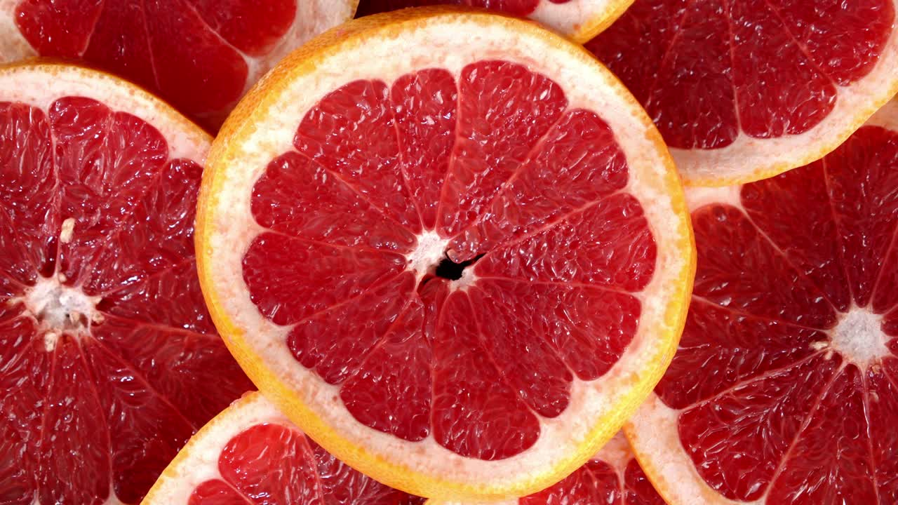 Red round slices of grapefruit slowly rotate.