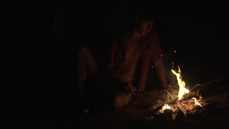 alone man sitting in front of the campfire in the dark