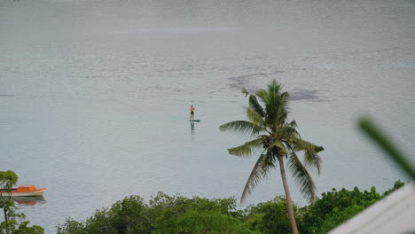 man chilling and stand-up paddleboarding during sunset at moso island in vanuatu