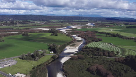 Aerial-drone-the-the-Grey-River-running-through-lush-green-landscape-near-Blackball,-New-Zealand