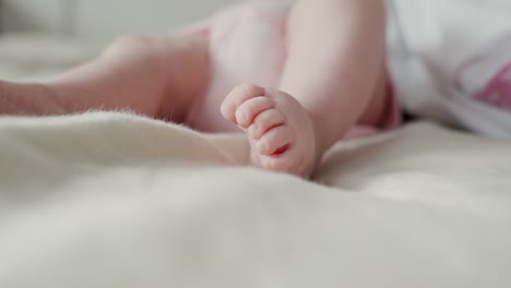 3 months old baby lying and moving in bed, focus on feet, copy space