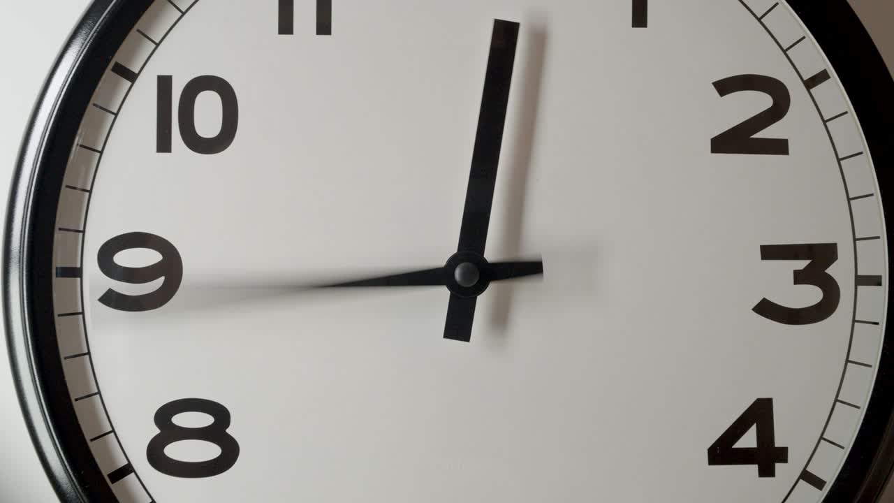 Primo piano del quadrante bianco dell'orologio in time-lapse su parete bianca.