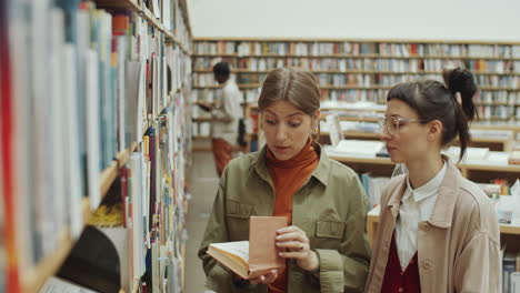 young women choosing book in library