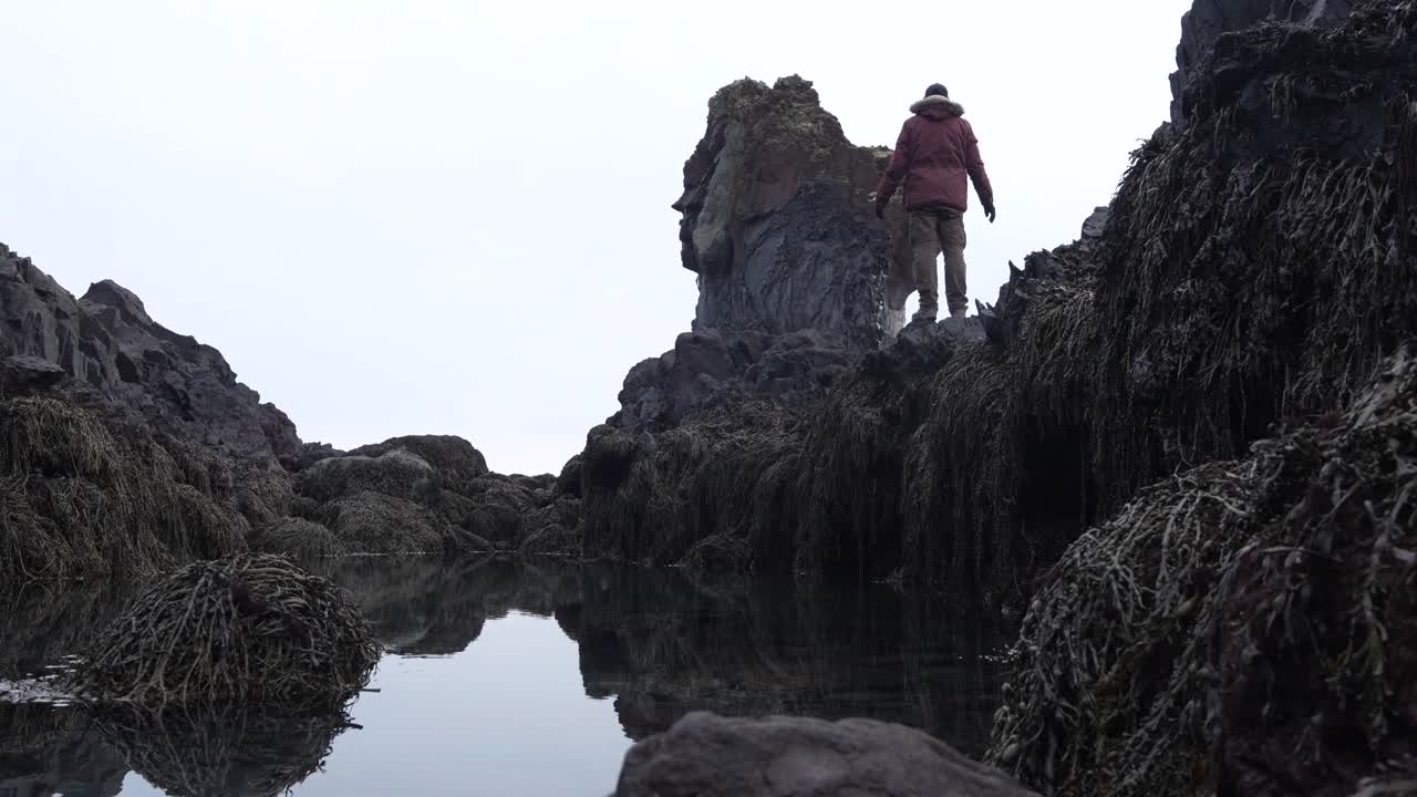 Homem explorando a costa rochosa