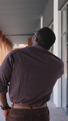 african american man talking the phone outdoors. back view of unrecognizable man solving business problems through the phone in the city. rear view. vertical video