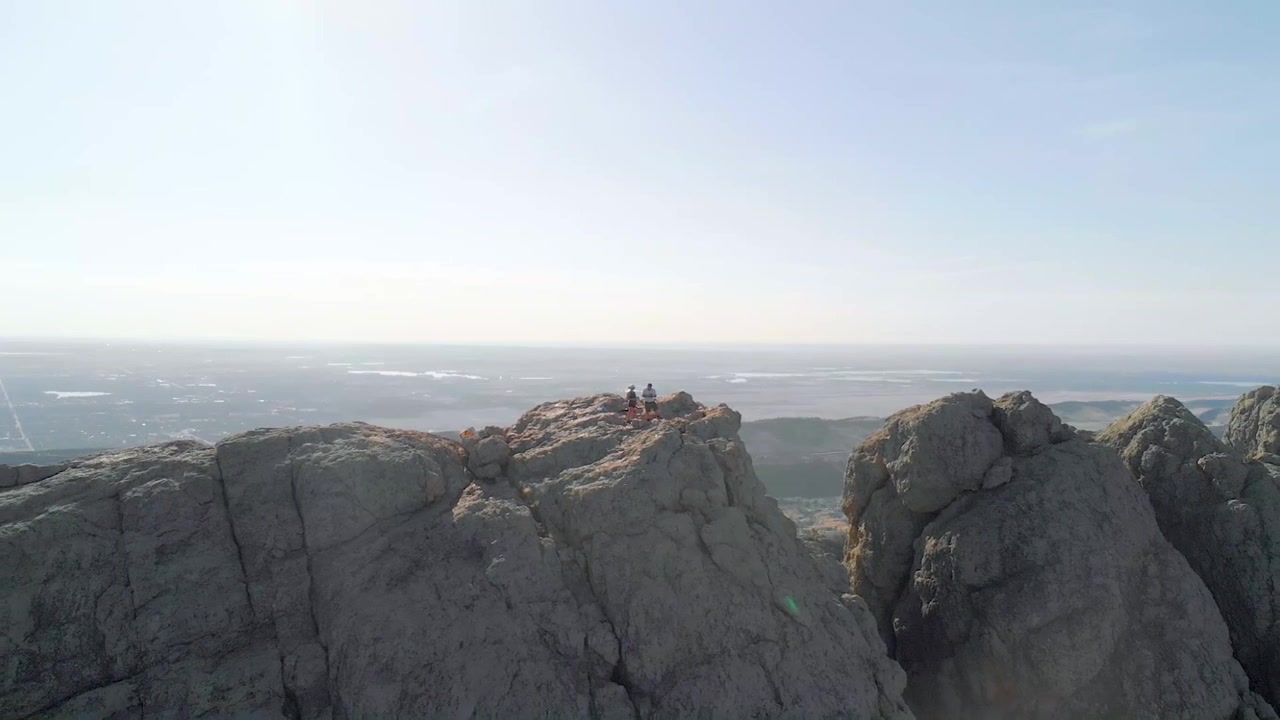 Drone shot of mountainous terrain, hikers and cityscape in the distance. The shots also feature aerial shots of lakes in the distance as well as flybys and other interesting features.