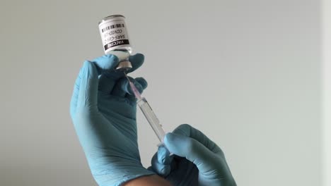 close up shot of nurse's hands wearing surgical gloves, holding syringe sucking out vaccine for covid-19