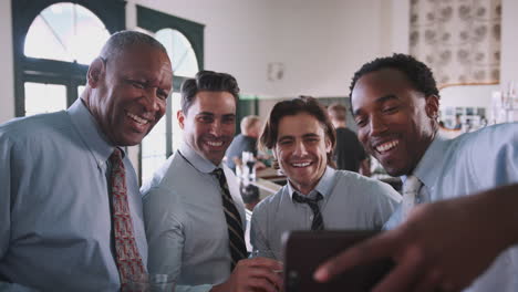 group of businessmen taking selfie in bar at after work drinks in bar