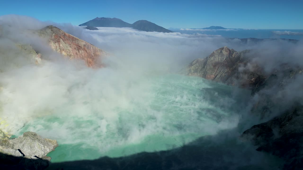 vista panorámica aérea del famoso volcán ijen y su cráter ácido del lago azul soplando humo en el aire en un día soleado - java oriental - indonesia