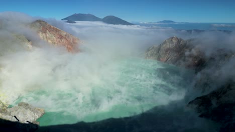 aerial panoramic view of the famous ijen volcano and its blue lake acid crater blowing smoke in the air in a sunny day - east java - indonesia