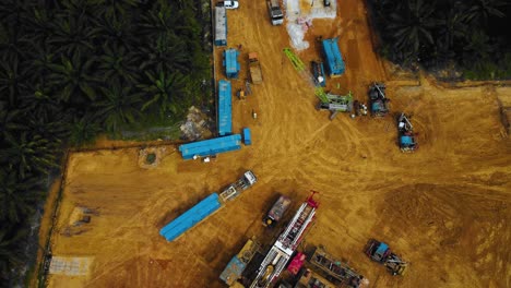 Cinematic-Drone-Footage-of-Onshore-Drilling-Rig-equipment-structure-for-oil-exploration-and-exploitation-in-the-middle-of-jungle-surrounded-by-palm-oil-trees-during-sunset-and-high-oil-price