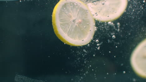 several lemon fruits fall inside a water tank and disturb water. three bright yellow lemon fruits fall inside a water tank and return to the surface