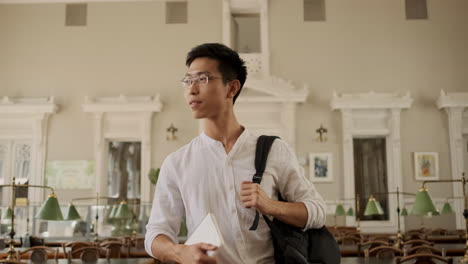 young asian male student walking through library