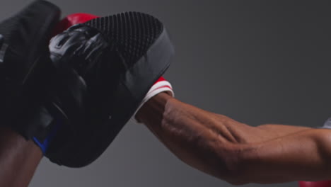 toma de cerca de un boxeador masculino luchando con un entrenador que usa guantes o guantes de puñetazos practicando para la pelea 4