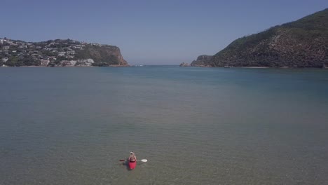 Kayakistas-Disfrutan-De-Un-Día-Soleado-En-La-Laguna-De-Knysna,-Cabezas-De-Knysna-Vistas-Más-Allá