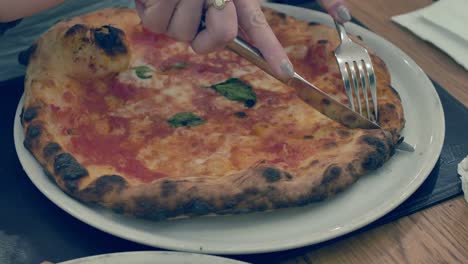 lady cutting hot steaming  pizza and sharing half