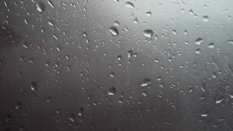 close up of rain water dripping and slipping down a wind screen