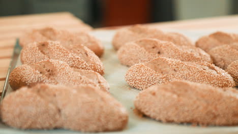 whole rack full of fresh and crunchy sesame bread rolls, freshly baked bread roll on baking sheet in the bakery