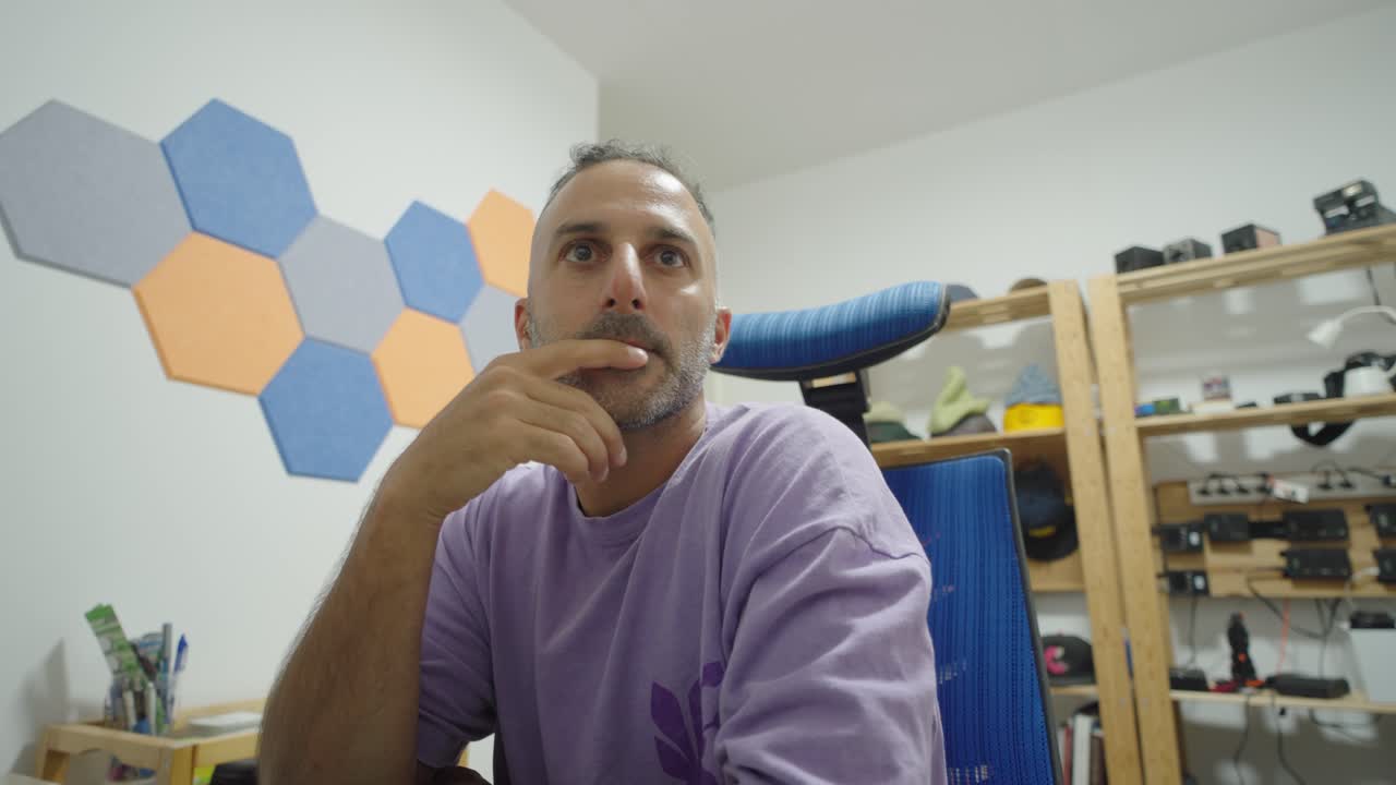 Casual home scene of a man at desk, slouched posture and thoughtful gaze, reflecting quiet solitude in ordinary surroundings