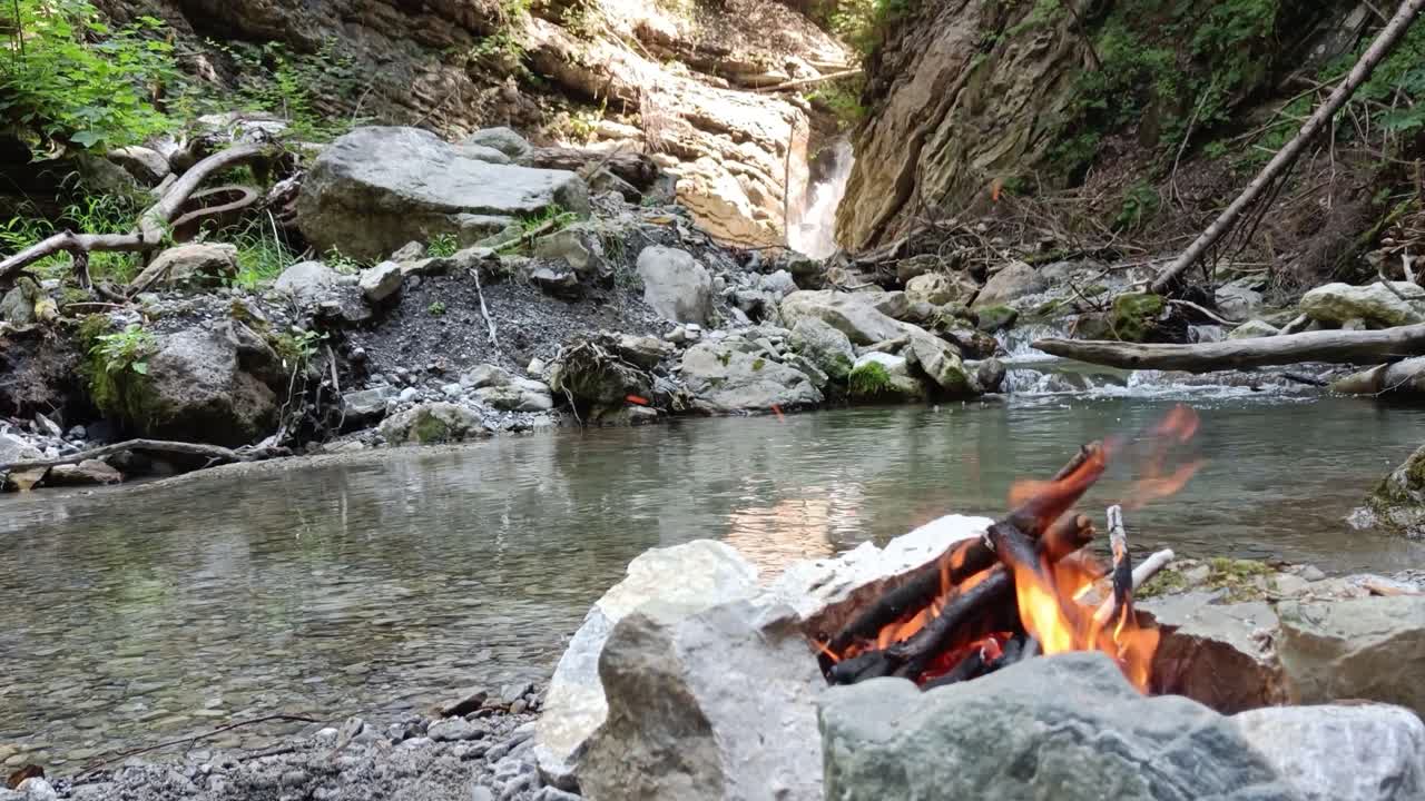 la hoguera arde pacíficamente en la naturaleza sin gente alrededor, rodeada de ríos y cascadas