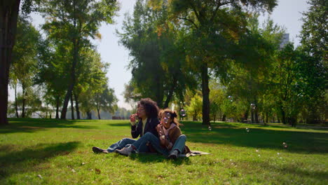 Familia-Alegre-Soplando-Burbujas-De-Jabón-Sentados-Juntos-En-Una-Manta-En-El-Parque-Soleado.