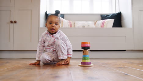 female toddler at home playing with wooden stacking toy