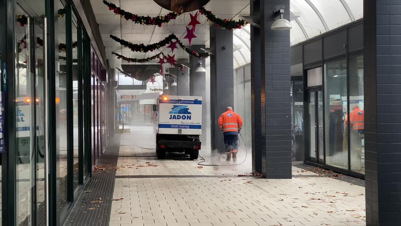 Cleaning company power washing shopping street while shops are under lockdown.