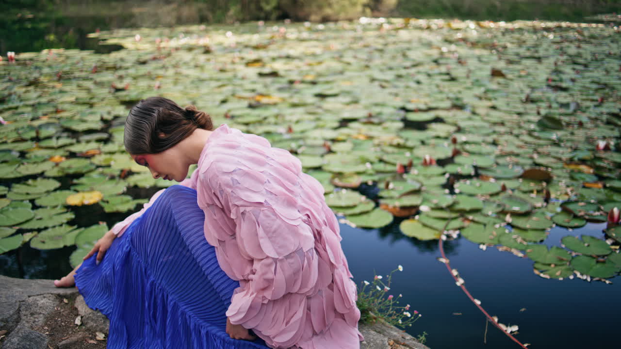 숲의 요정이 앉아 있는 호수, 인 수리리, 가까운 곳에서 꿈꾸는 여자가 포즈를 취하고 있다.