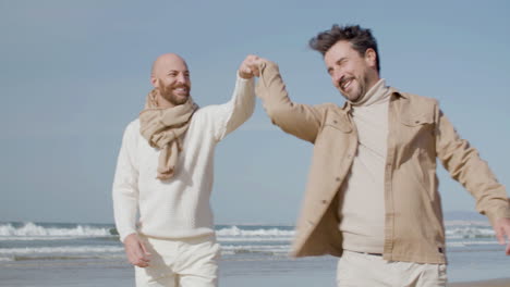 tracking shot of a happy gay couple dancing on the beach