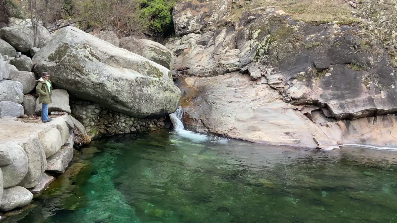 Blonde girl exploring a transparent green natural pool in Ávila, Spain