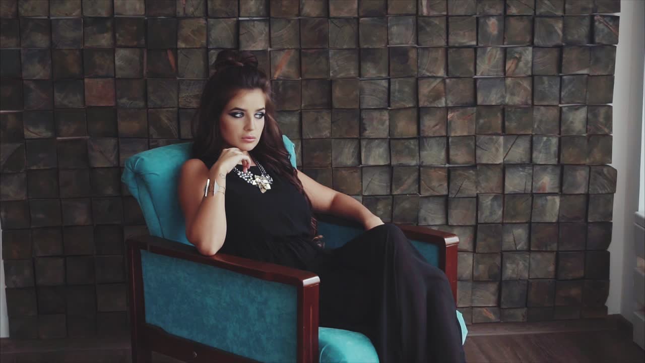 женщина в черном платье сидит в синем кресле