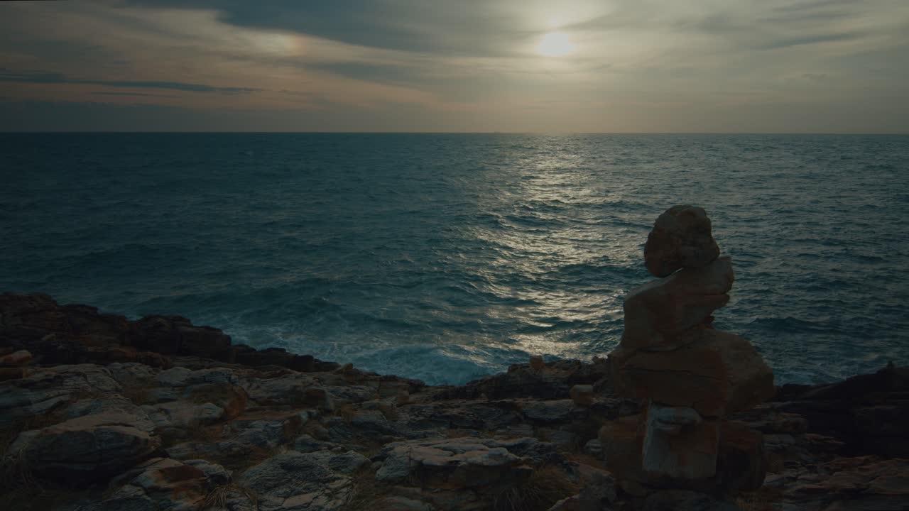 Tramonto costiero con ometto di pietra
