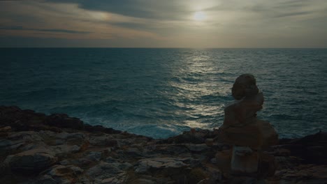 coastal sunset with stone cairn