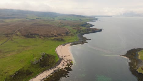 Aerial drone shot of Coral Beach on the Isle of Skye, Scotland, with turquoise waters, white sand, and surrounding green hills creating a stunning coastal landscape