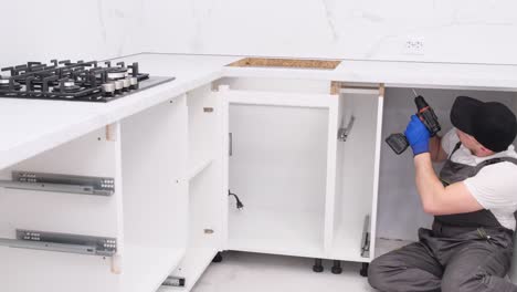 busy handyman in overalls installing new kitchen furniture indoors