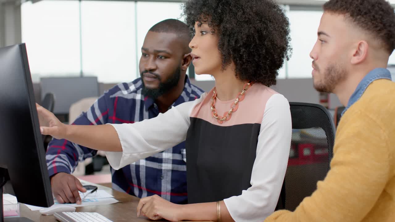 Three diverse male and female colleagues discussing over a computer at office