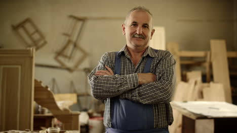 positive man looking in camera indoors. carpenter standing with crossed arms