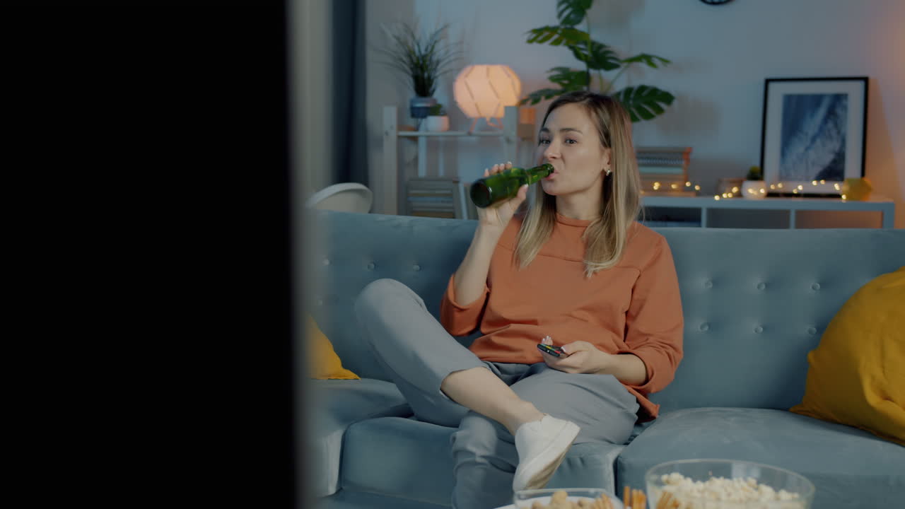 Woman Relaxing on Couch, Watching TV and Drinking Beer