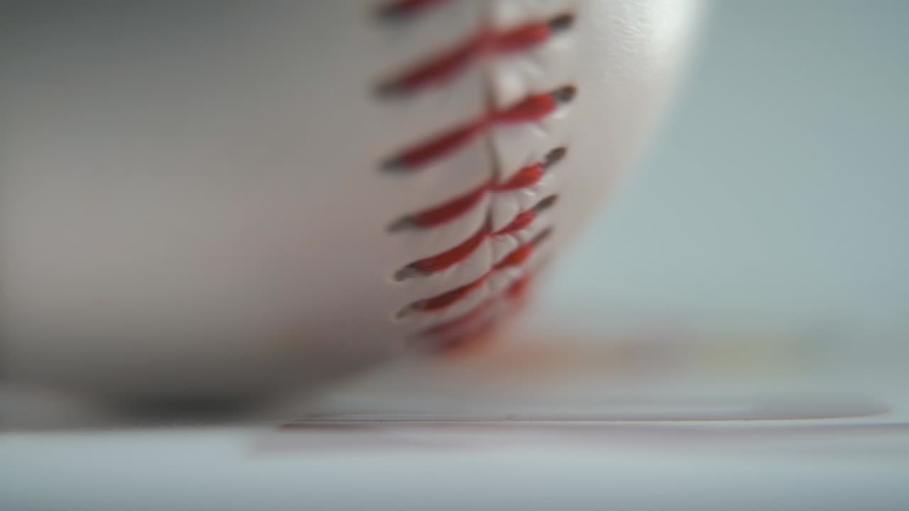 Cinematic macro shot of a rotating white base ball, close-up on red stitches, baseball rotate, professional studio lighting, smooth hyper slow motion 120 fps close-up