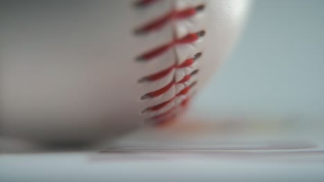 cinematic macro shot of a rotating white base ball, close-up on red stitches, baseball rotate, professional studio lighting, smooth hyper slow motion 120 fps close-up