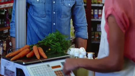 Smiling-female-staff-weighting-vegetables-on-scale