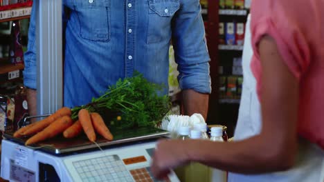 una mujer sonriente pesa verduras en la balanza.