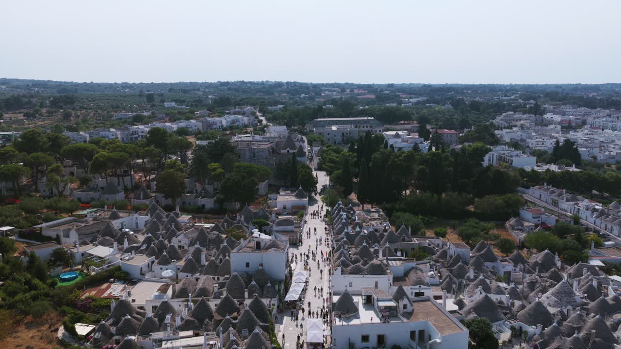 Aerial view over historic Alberobello. Shows unique trulli houses with conical roofs. Tourists walk through UNESCO World Heritage site. For travel or documentary use, Puglia, Italy