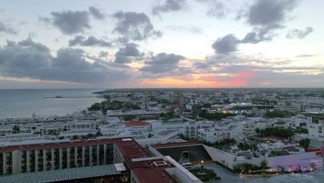 aerial view of a cityscape by the coast, with built structures, rolling clouds and endless horizon on magic hour in playa del carmen, mexico