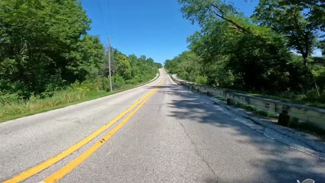 pov - driving on a secondary road with wooden barricades to protect cyclists on the bike trail next to road